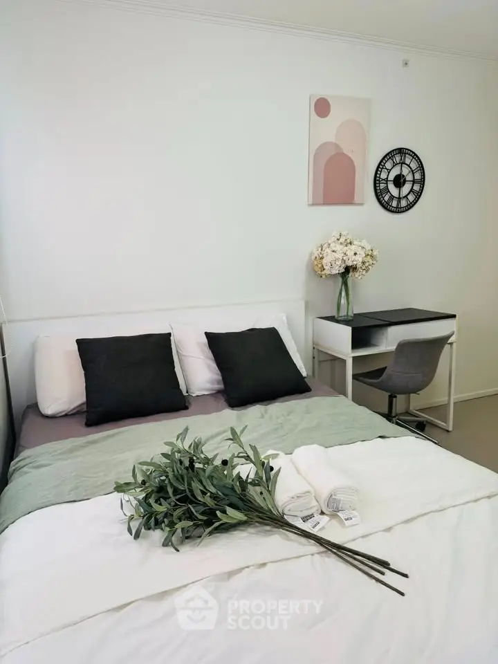 Modern bedroom with stylish decor and workspace, featuring a cozy bed and elegant wall art.