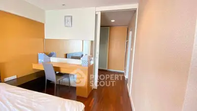Modern bedroom with wooden flooring and study desk, featuring a sleek design and ample natural light.