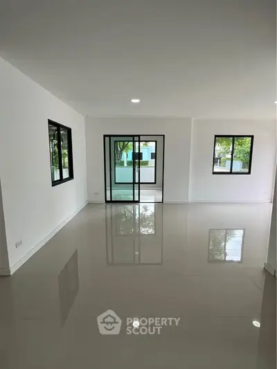 Spacious modern living room with large windows and glossy tiled floors