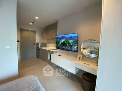 Modern studio apartment with sleek design, featuring a wall-mounted TV, compact kitchen, and stylish decor.