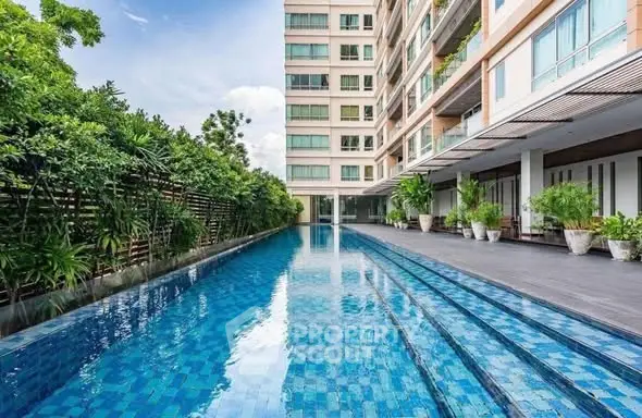 Luxurious apartment building with a stunning outdoor pool and lush greenery.