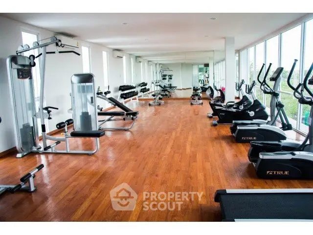Spacious gym with modern equipment and large mirrors in a residential building.