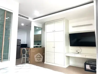 Modern bedroom with built-in wardrobe and wall-mounted TV in a stylish apartment.