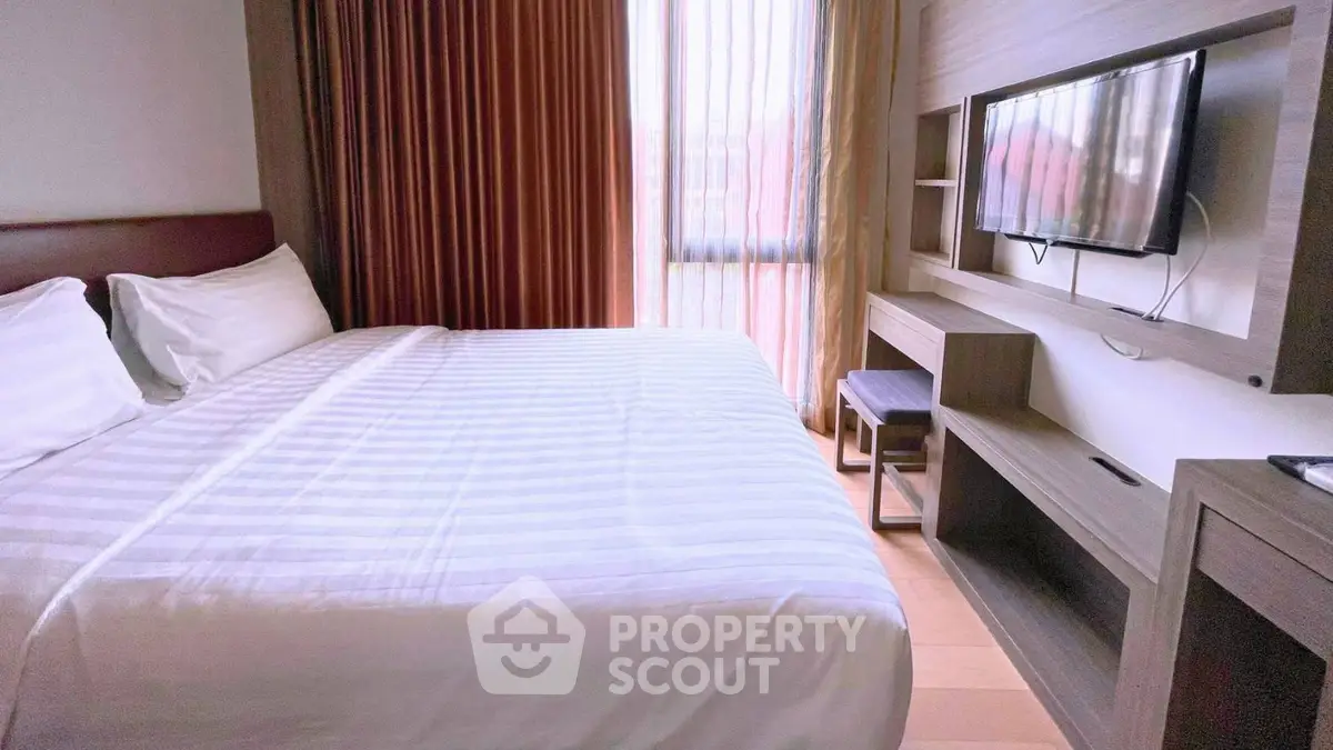 Cozy bedroom with modern furnishings and wall-mounted TV, perfect for relaxation.