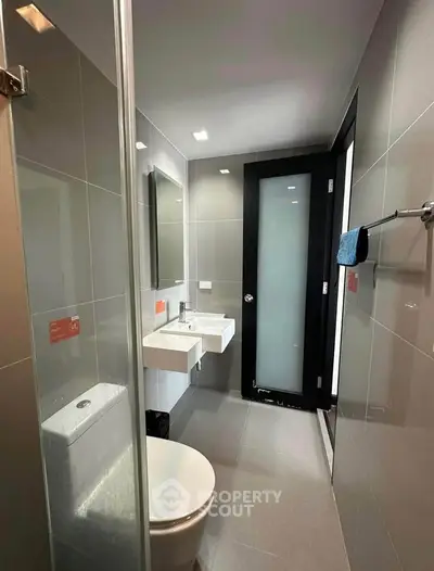 Modern bathroom with sleek fixtures and glass shower in contemporary apartment.