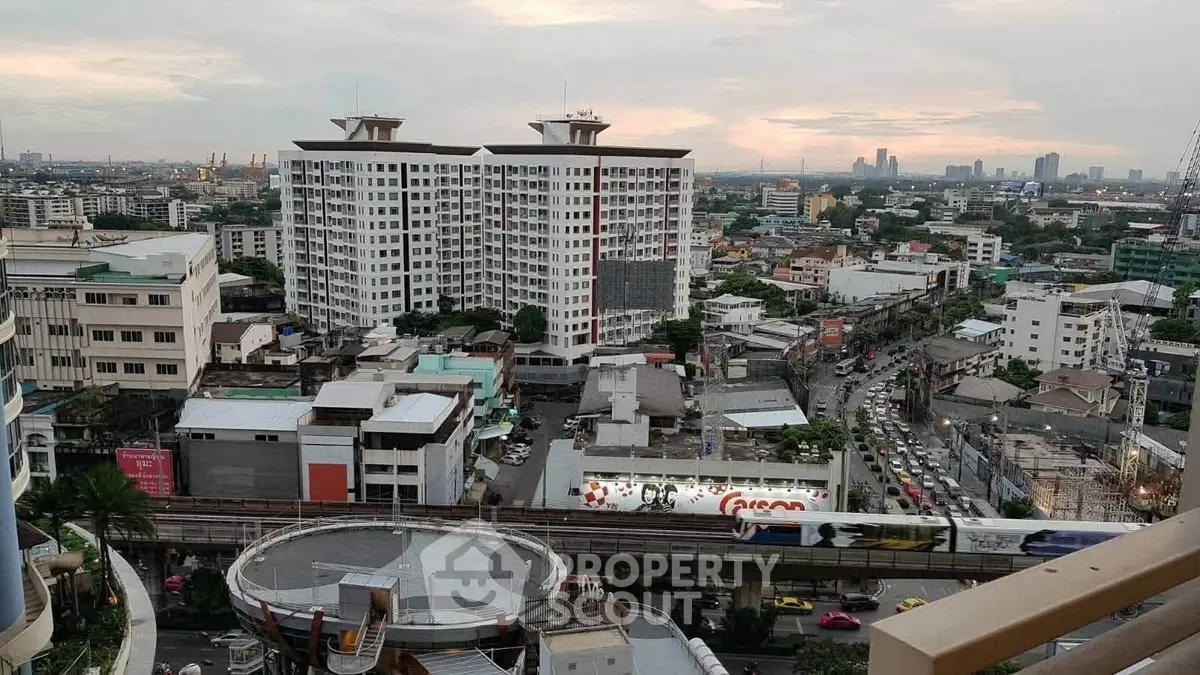 Stunning cityscape view from a high-rise building balcony at sunset, showcasing urban skyline and bustling streets.