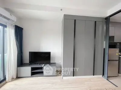 Modern living room with sleek TV stand and large wardrobe, featuring sliding glass doors for natural light.