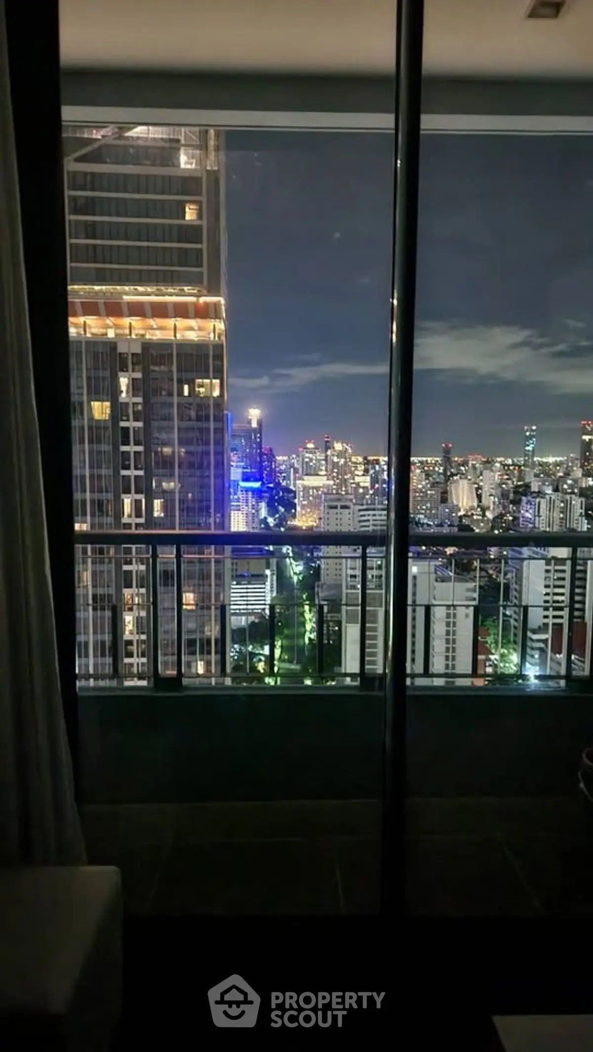 Stunning cityscape view from high-rise balcony at night, showcasing vibrant urban lights.