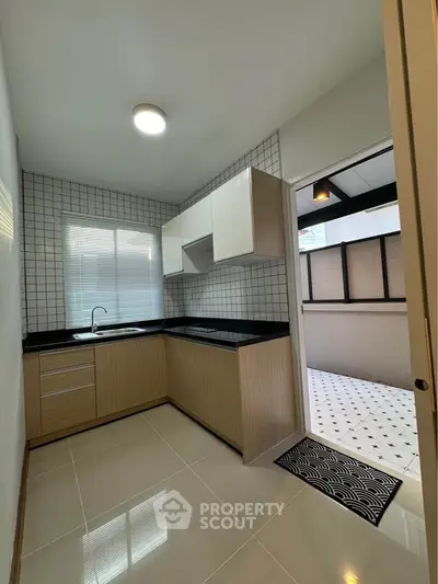 Modern kitchen with sleek cabinetry and tiled backsplash, adjacent to a bright outdoor area.