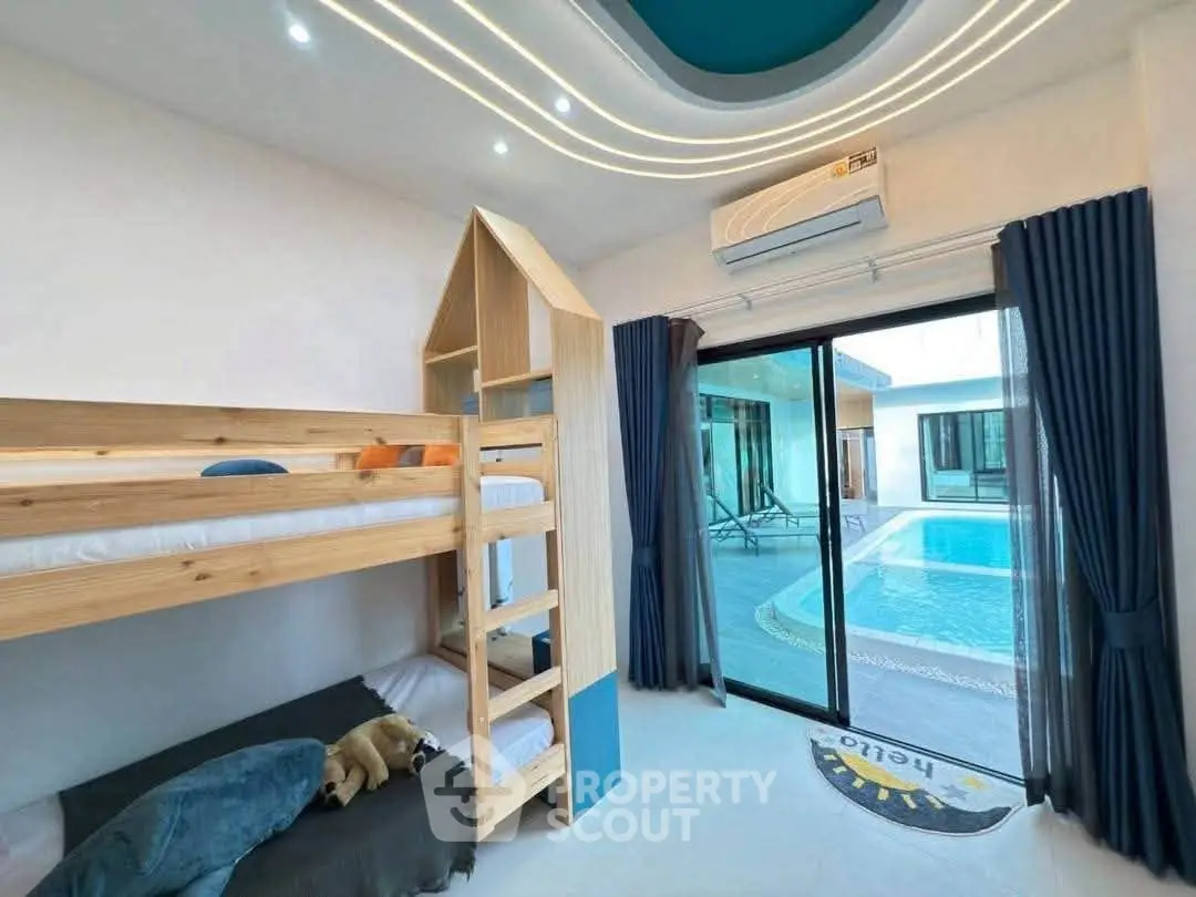 Modern bedroom with bunk bed and pool view, featuring sleek design and ample natural light.