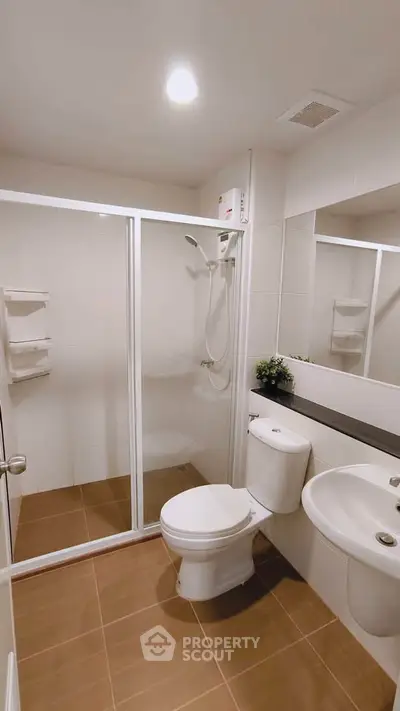 Modern bathroom with glass shower enclosure and sleek fixtures in a contemporary apartment.
