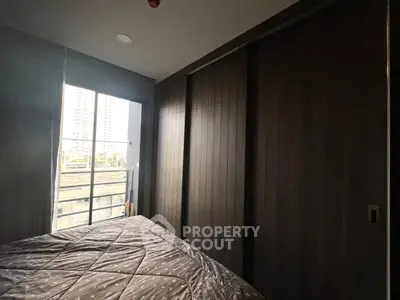 Cozy bedroom with large window and modern sliding wardrobe in urban apartment