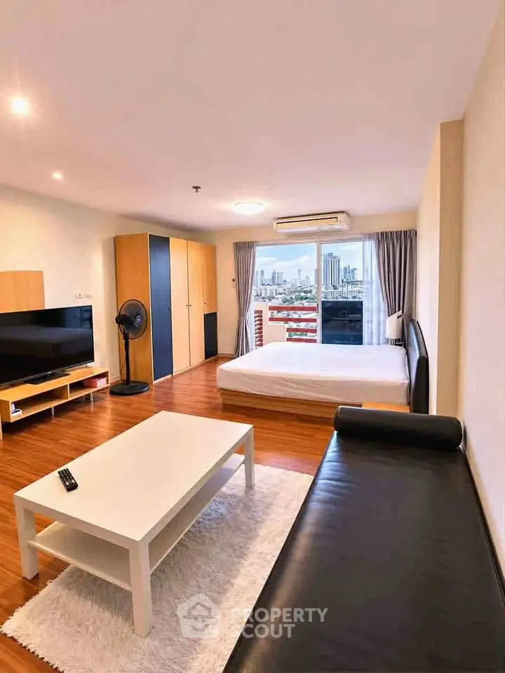 Spacious studio apartment with modern furnishings and city view balcony.