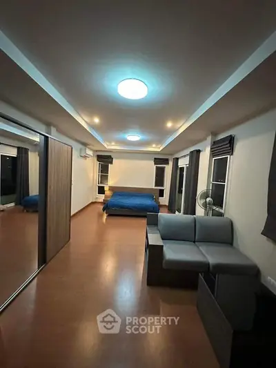 Spacious bedroom with modern lighting and large windows for natural light.