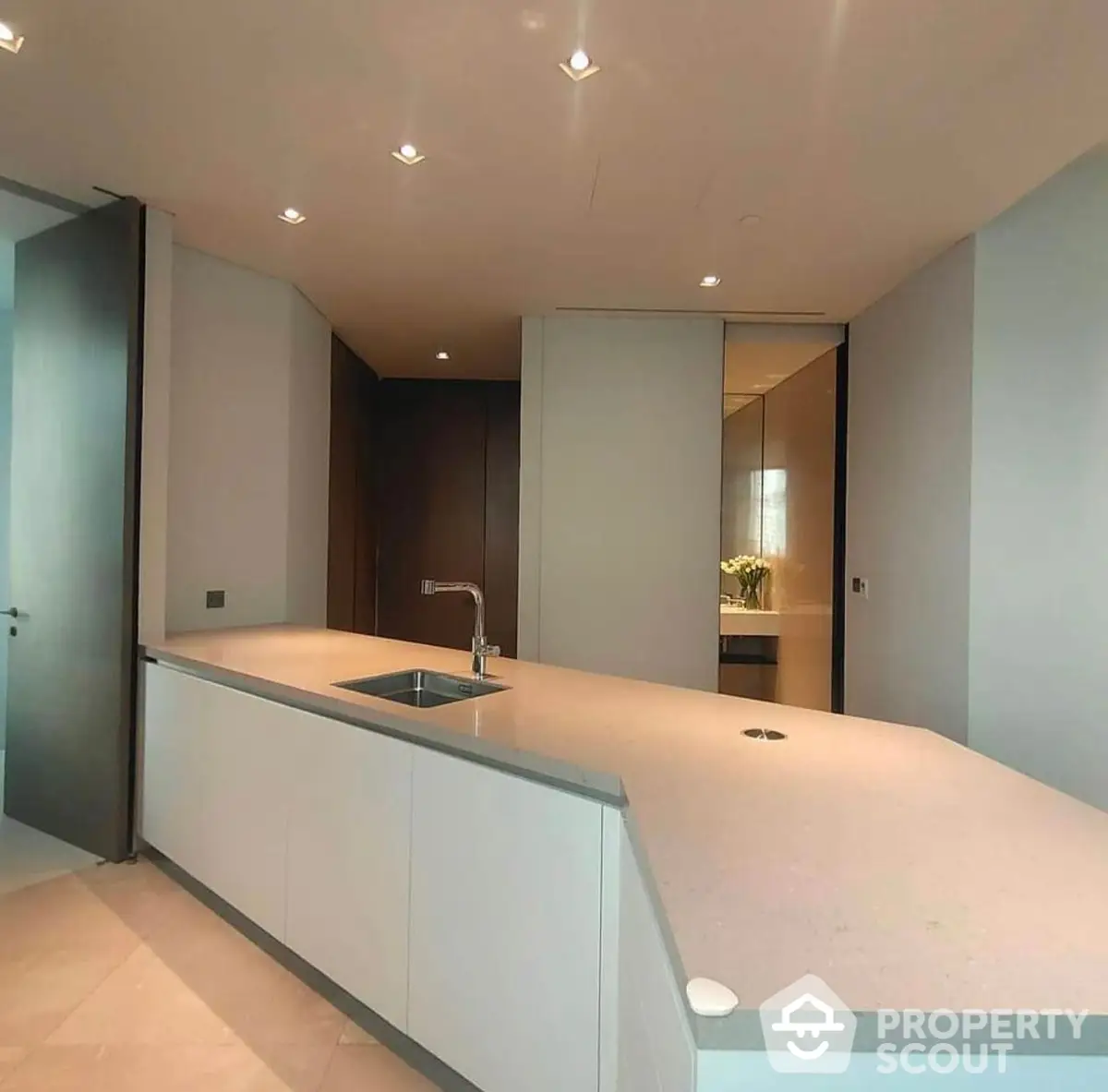 Sleek modern kitchen with integrated appliances and ample counter space, featuring a minimalist design and neutral tones.