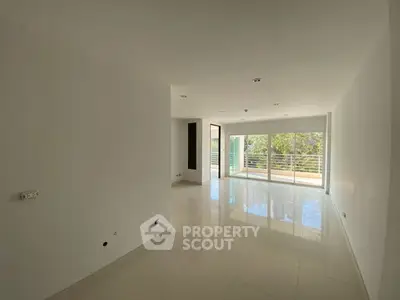 Spacious empty living room with large windows and balcony access.