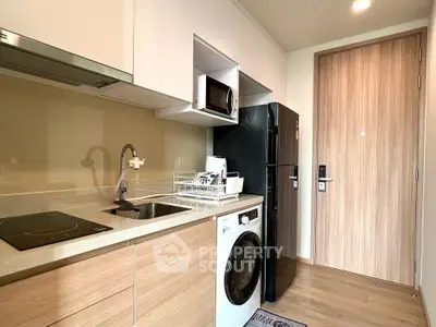 Modern kitchen with sleek appliances and wooden cabinetry in a compact layout.