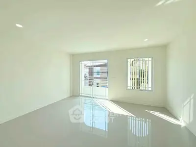 Spacious sunlit living room with large windows and glossy floors in modern home.