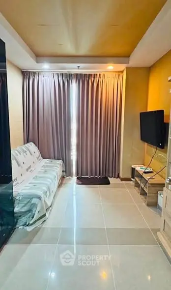 Modern living room with sleek tile flooring, cozy sofa, and wall-mounted TV, perfect for relaxation.