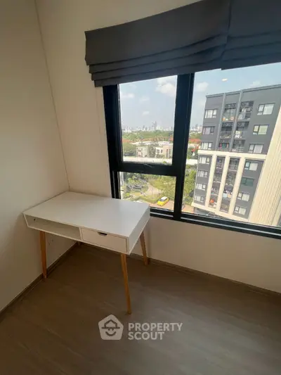 Bright study area with city view and modern desk in high-rise apartment.