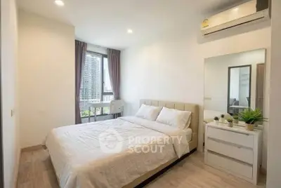 Modern bedroom with city view, featuring a comfortable bed and sleek decor.