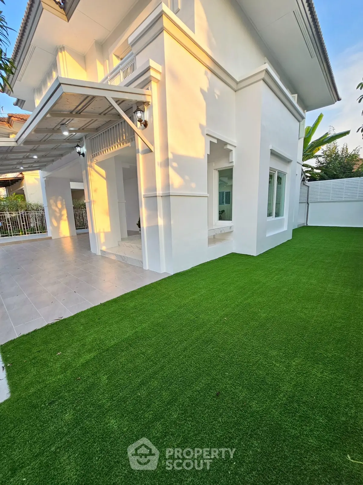 Charming white house with lush green lawn and spacious patio, perfect for family gatherings.
