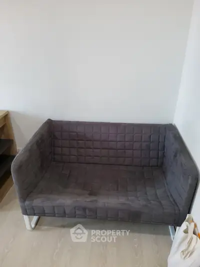 Modern gray sofa in a minimalist living room setting with light wood flooring.
