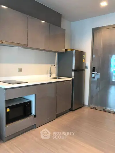Modern kitchen with sleek cabinets, built-in microwave, and stainless steel fridge in a stylish apartment.