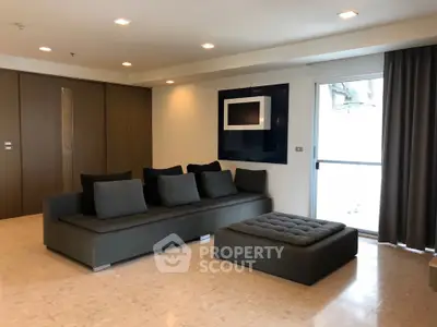 Spacious modern living room with elegant gray sofa and large window for natural light.