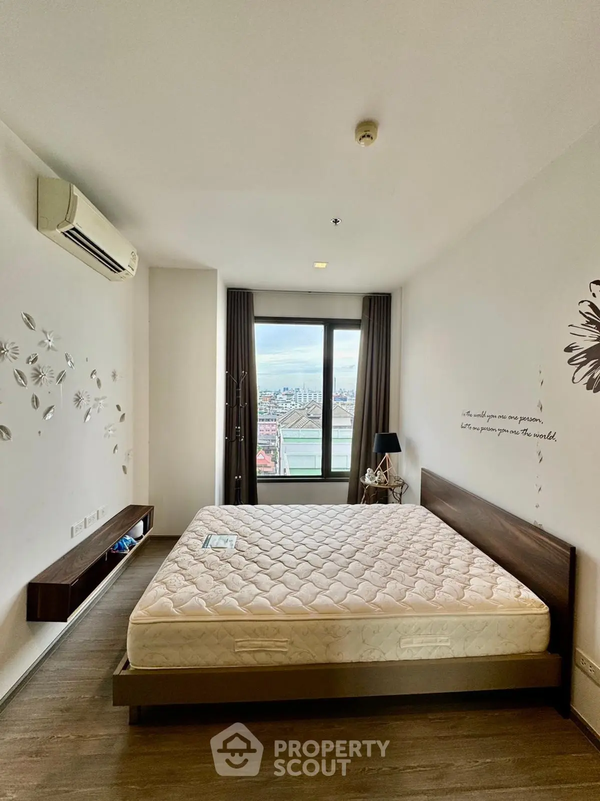 Spacious bedroom with city view, modern decor, and air conditioning in a high-rise apartment.