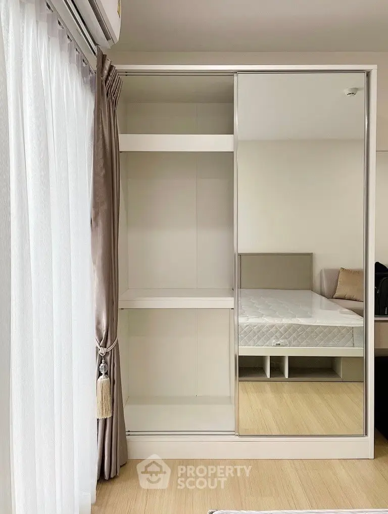 Modern bedroom with mirrored wardrobe and elegant curtains, showcasing minimalist design and natural light.