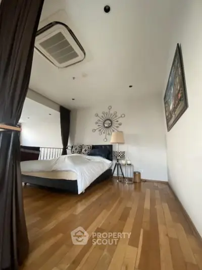 Stylish bedroom with modern decor and wooden flooring, featuring a cozy bed and elegant wall art.