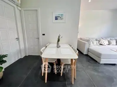 Modern dining area with sleek table and cozy living room in stylish apartment.
