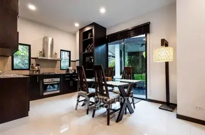 Modern kitchen with open layout and dining area, featuring sleek cabinetry and large windows for natural light.
