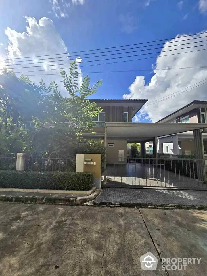 Modern two-story house with spacious driveway and lush greenery under a clear blue sky.