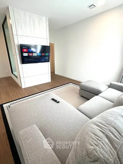 Modern living room with sleek TV setup and comfortable gray sectional sofa.