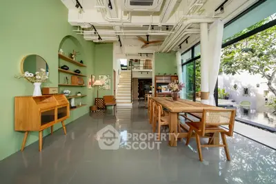 Spacious modern living room with green accents and large windows opening to garden view.