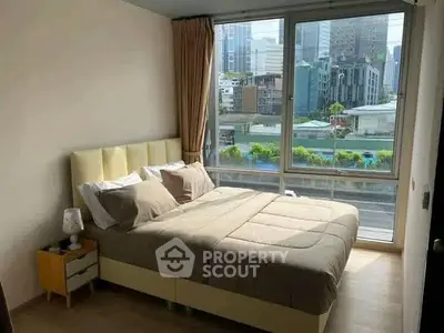 Modern bedroom with city view, featuring large windows and stylish decor.