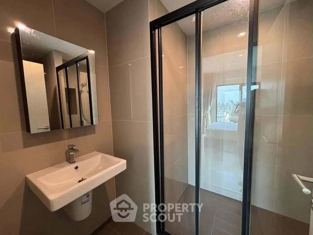 Modern bathroom with sleek shower and stylish sink in urban apartment.