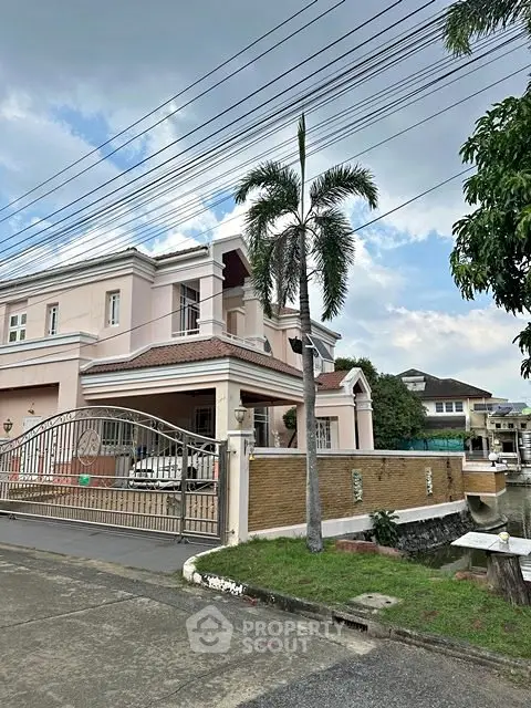 Elegant two-story house with gated entrance and palm tree, showcasing a serene residential neighborhood.