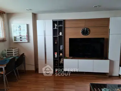Modern living room with sleek white cabinets and wall-mounted TV, featuring wooden flooring and stylish decor.