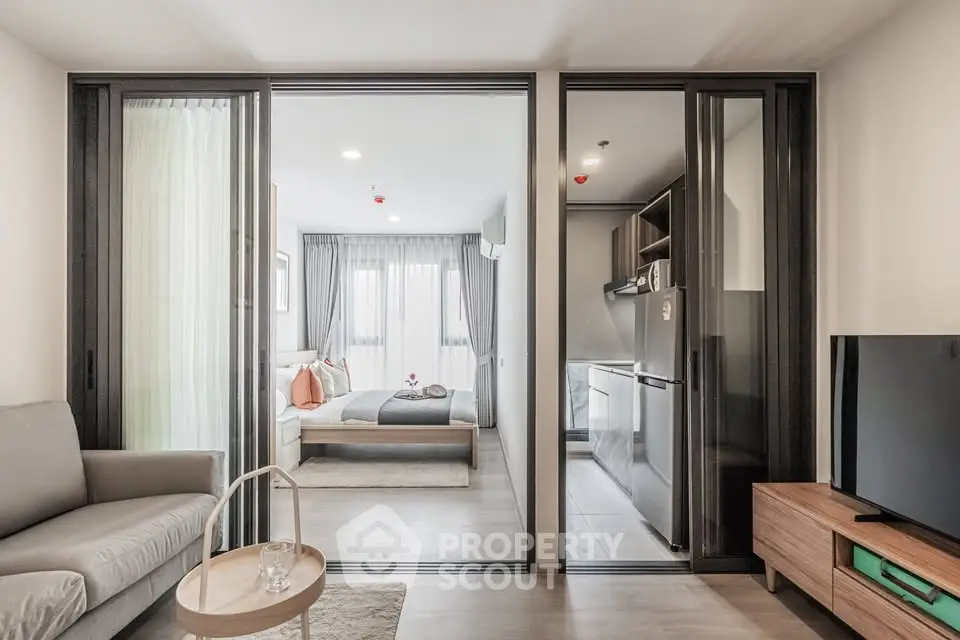 Modern open-plan apartment with sleek kitchen and cozy living area, featuring stylish decor and ample natural light.