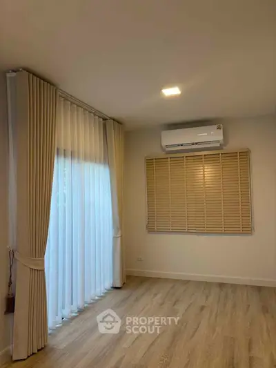 Spacious room with elegant curtains and modern air conditioning, perfect for comfortable living.