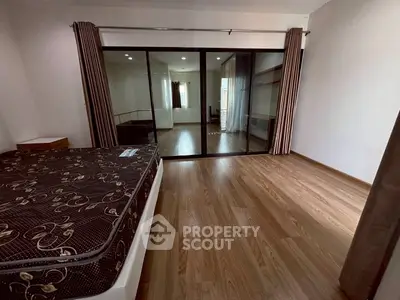 Spacious bedroom with wooden flooring and large glass doors leading to a bright adjoining room.
