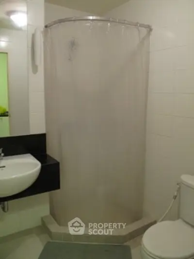 Compact bathroom with corner shower and modern fixtures.