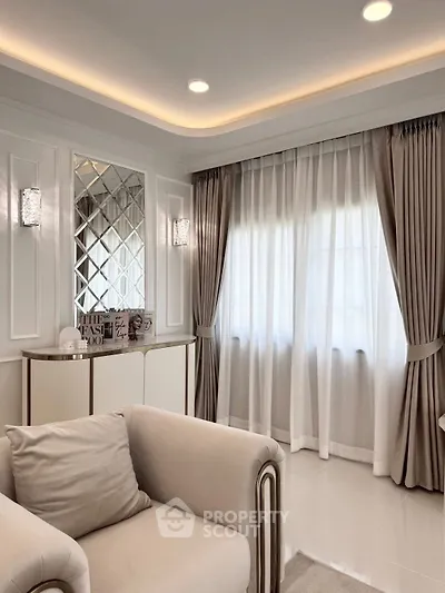Elegant living room with plush seating and stylish decor, featuring large windows with luxurious curtains.