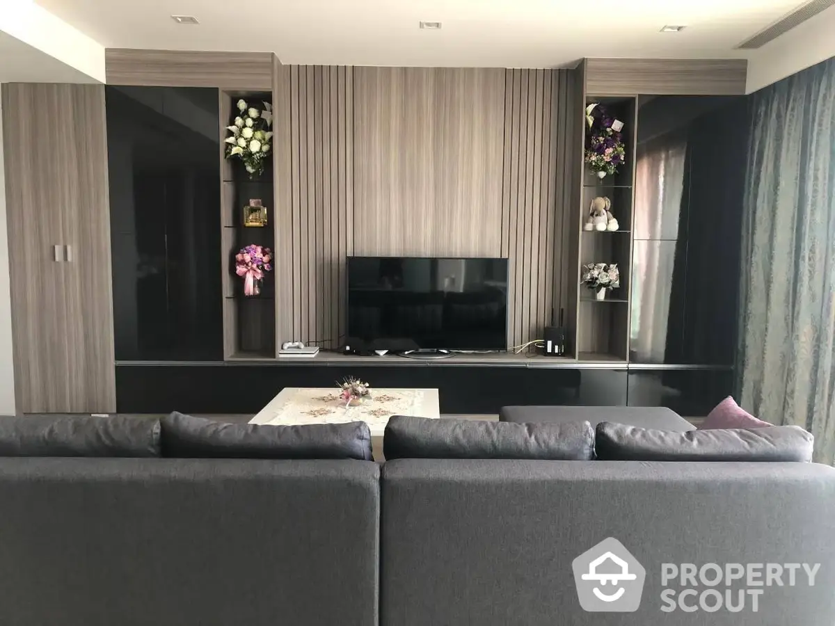 Elegant living room with modern furnishings, sleek entertainment unit, and tasteful floral accents creating a luxurious ambiance.