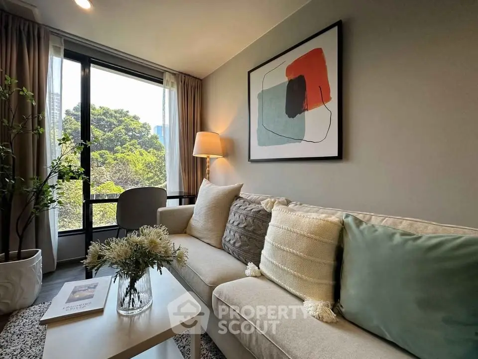 Stylish living room with modern decor and large window offering lush green views.