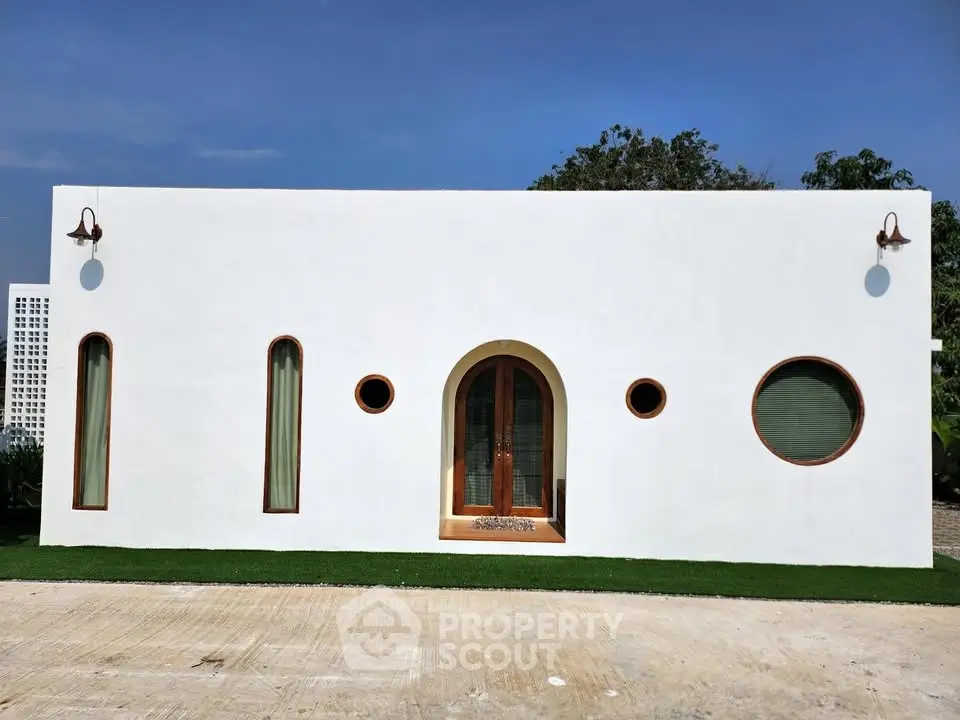 Modern minimalist white house with unique circular windows and wooden door