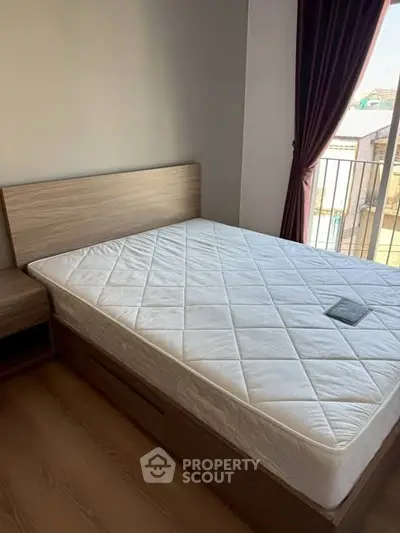 Cozy bedroom with wooden bed frame and balcony view, perfect for relaxation.